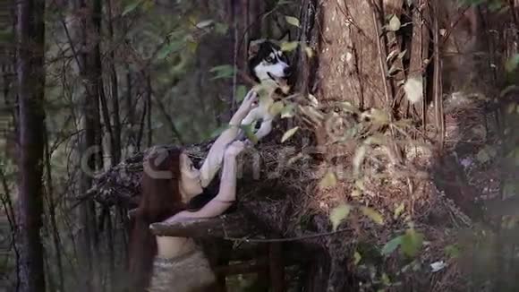 穿着野衣服的年轻女子用爪子抓着一只看起来像狼的狗视频的预览图