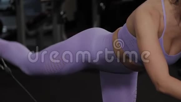 有着美丽身材的运动女性在健身房的街区模拟器上训练臀部视频的预览图
