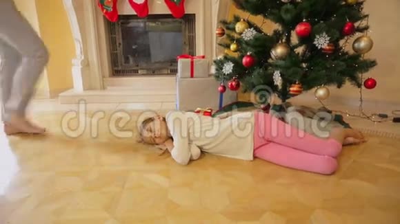 可爱的女孩在圣诞树下睡着了妈妈叫醒她送圣诞礼物视频的预览图