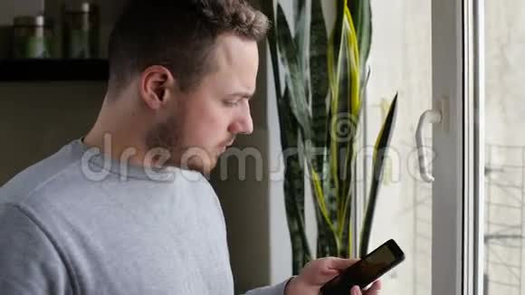 早上一个年轻人在一扇带咖啡的窗户上用手机说话视频的预览图