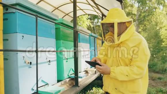 养蜂人用平板电脑检查木制蜂箱然后在养蜂场收获蜂蜜视频的预览图