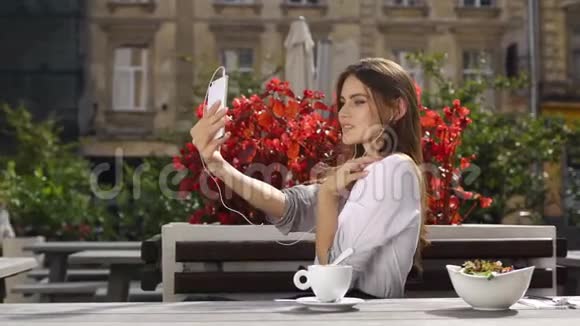 布鲁内特女士一边坐在餐厅一边对着红花一边用耳机在电话里讲话视频的预览图