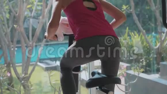 特写女性腿并在健身房骑着静止自行车慢动作视频的预览图