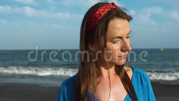 一个女人穿着漂亮的蓝色裙子在黑色火山海滩上的肖像视频的预览图