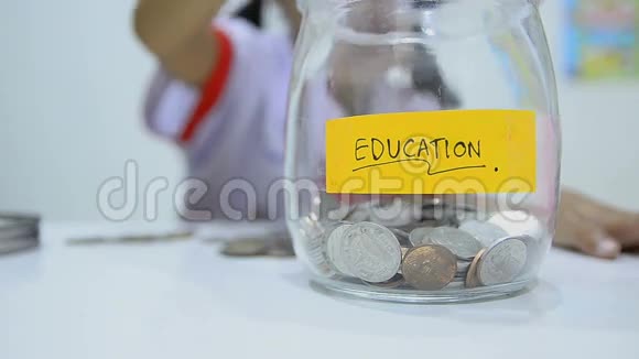 近镜头亚洲小女孩穿着泰国学生制服硬币和玻璃瓶省钱的概念视频的预览图