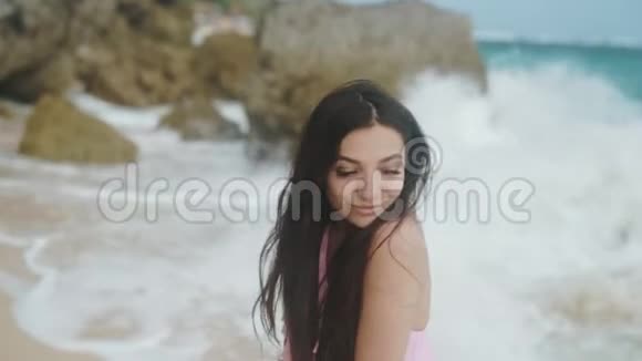 慢镜头穿着泳装的快乐女孩的肖像在海滩上放松背景上有美丽的波浪稳定的镜头视频的预览图