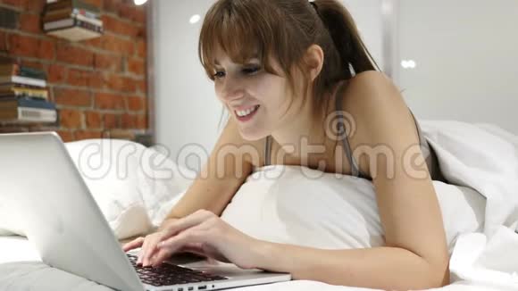 夜间躺在床上的妇女上网聊天视频的预览图