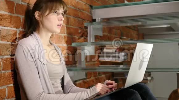 穿着笔记本电脑坐在楼梯上的进攻性思考女视频的预览图