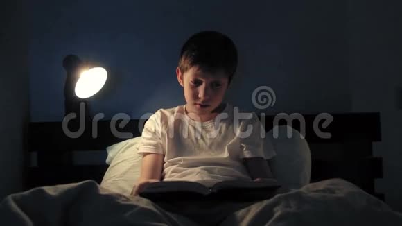 男孩晚上躺在床上看书会使光线变暗然后睡觉视频的预览图