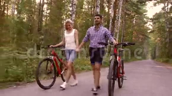 快乐的一对夫妇骑着自行车在森林里散步视频的预览图