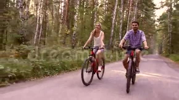 快乐的一对夫妇在夏天公园骑自行车玩的肖像视频的预览图