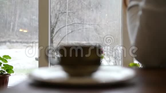 窗外的森林里下着雪焦点转移到咖啡馆里的一杯热茶慢动作1920x1080满视频的预览图