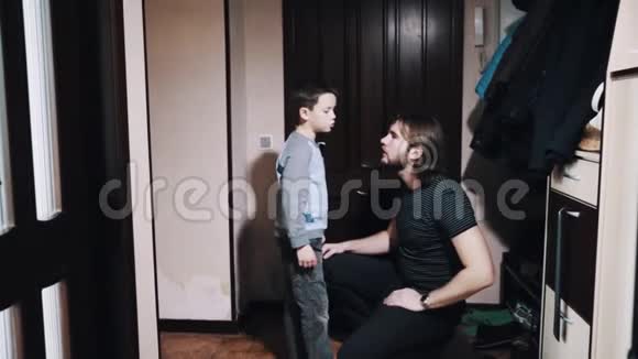小男孩在公寓走廊里和长头发的父亲说话视频的预览图