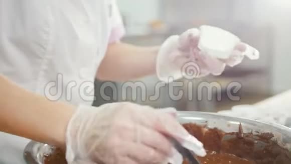 面包师把巧克力奶油混合在金属碗里做蛋糕视频的预览图