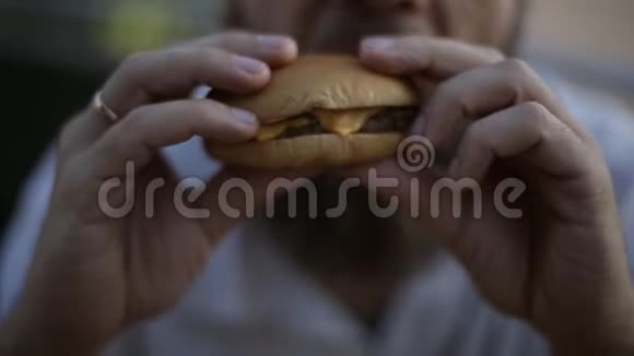 一个长着胡子的白种人晚上坐在夏季咖啡馆的一张桌子上吃汉堡包快关门视频的预览图