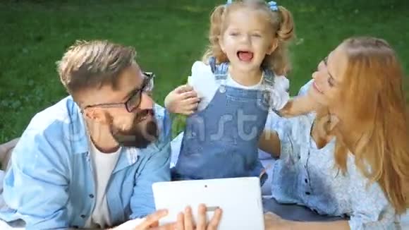 暑假家庭孩子科技理念带平板电脑的公园微笑家庭视频的预览图