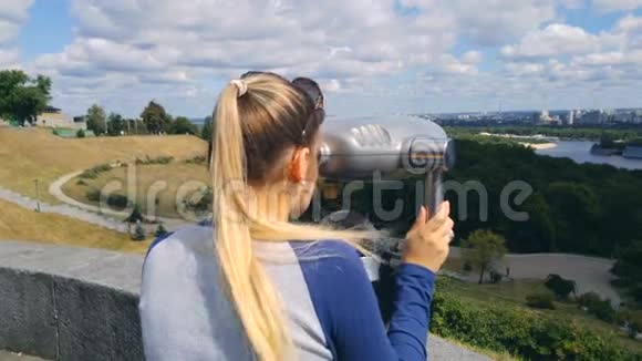 美丽的女游客在高山上使用硬币付费望远镜观看城市景观视频的预览图