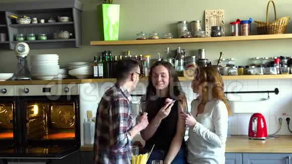 两个女孩和男孩庆祝生日喝香槟在厨房吃蛋糕玩得开心视频的预览图