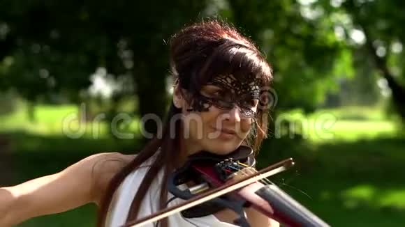 美丽的年轻女孩在美丽的公园里拉电小提琴视频的预览图