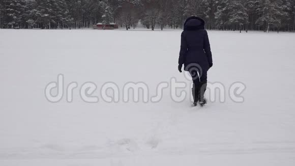 女人在雪地里行走在冬天形成心形脚印4K视频的预览图