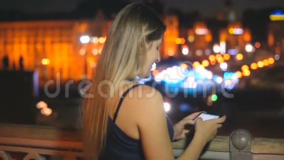 晚上在屋顶上用智能手机的美女视频的预览图