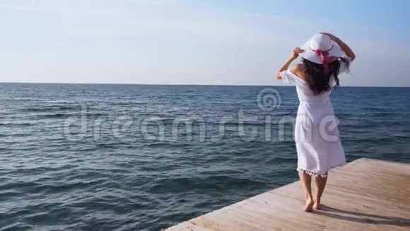 年轻女子站在木墩上望着大海视频的预览图