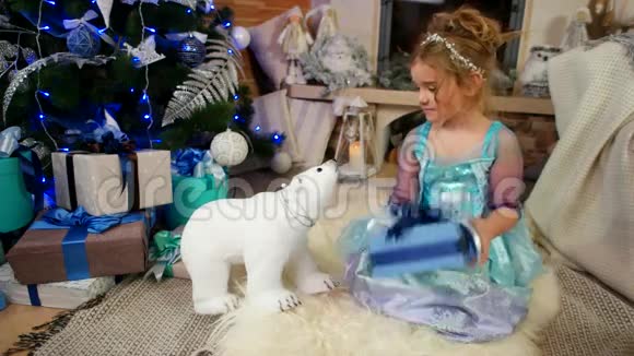 可爱的小女孩在玩玩具和礼物圣诞礼物精美的包装纸盒与蝴蝶结礼物视频的预览图