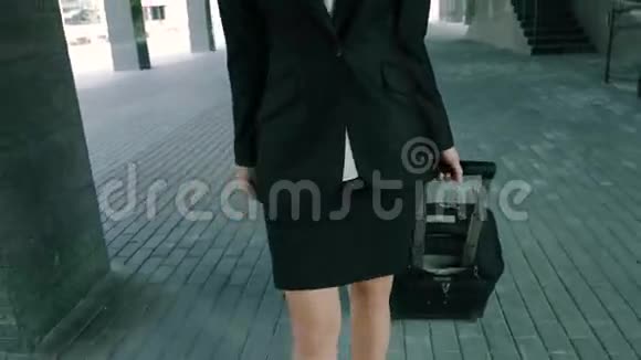 一位漂亮的金发女商人带着旅行行李走进办公楼视频的预览图