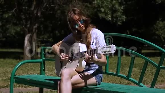 美丽的年轻时髦女孩在公园玩吉他视频的预览图