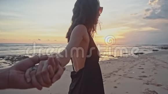 年轻夫妇牵着手女人牵着男朋友在空荡荡的海滩上走向日落海上暑假快乐视频的预览图