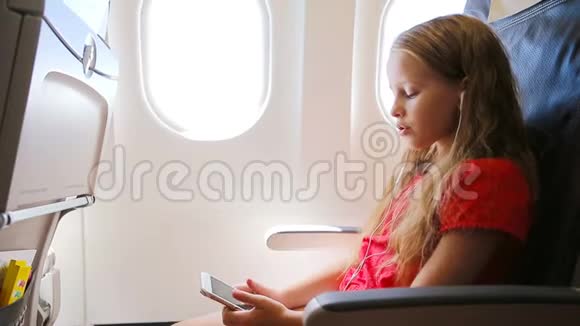 可爱的小女孩坐飞机坐在窗边小孩坐在飞机窗前听音乐视频的预览图
