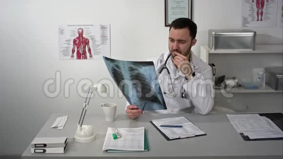一位严肃的医生坐在桌子旁看病人x光视频的预览图