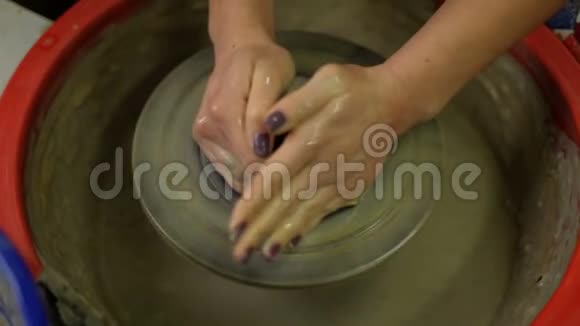 女孩在陶工的轮子上做了一个陶器花瓶一个女孩用她的手在陶工车轮上形成粘土视频的预览图