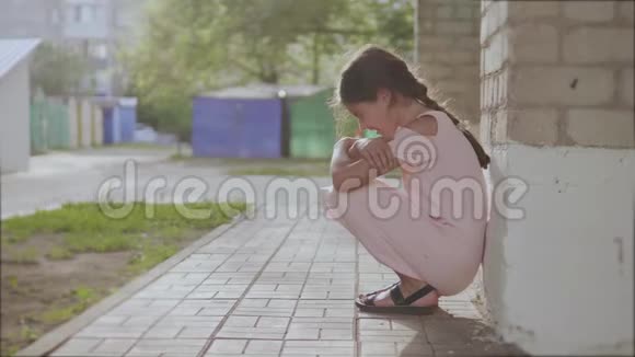 悲伤的小女孩坐在砖头旁边的墙上沮丧的慢动作视频生活方式女孩青少年烦躁情绪视频的预览图