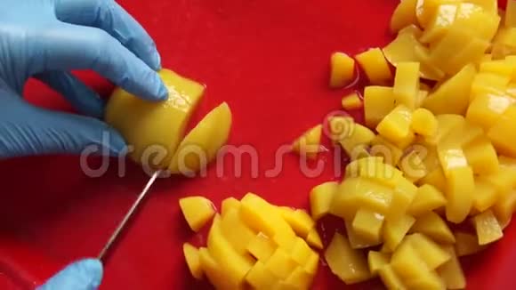 用手用刀把黄色芒果切成碎片制成食品视频的预览图