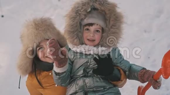 母亲抱着可爱的小女儿在冬季公园享受寒冷的阳光天气视频的预览图