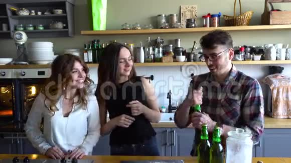 这家伙打开瓶子和面包和厨房里的女孩一起喝啤酒和丁克瓶视频的预览图
