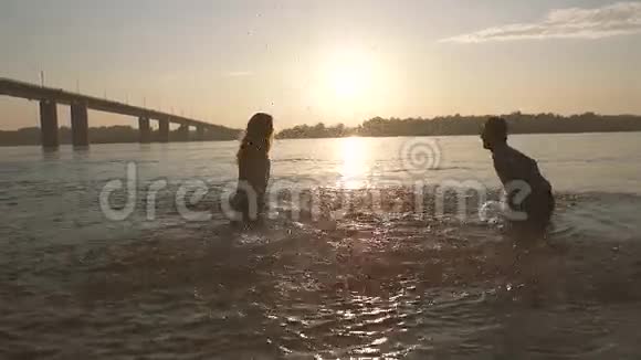 一对快乐的年轻夫妇在炎热的夏天晚上在水中嬉戏视频的预览图