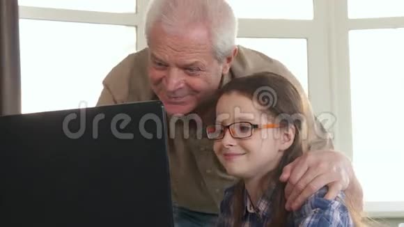 小女孩和她爷爷在笔记本电脑上视频聊天视频的预览图
