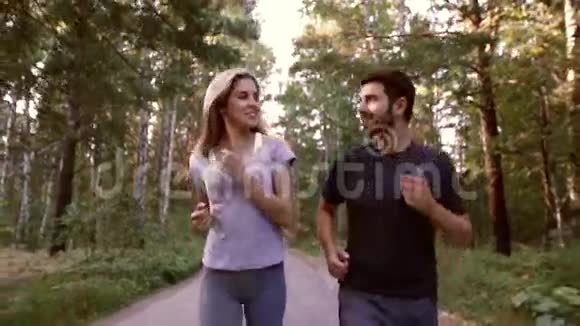 欢快的金发女人和英俊的男人一起在森林里慢跑的肖像视频的预览图