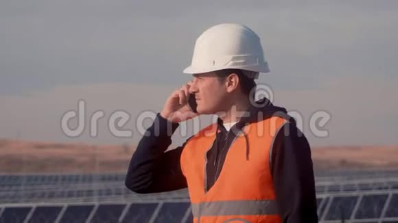 一个戴着头盔的人在一家太阳能发电厂的背景下拿着一平板电脑视频的预览图