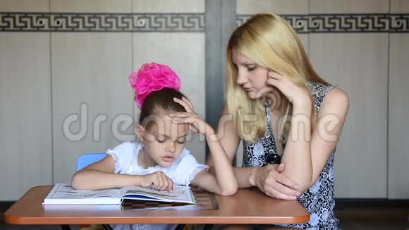 女学生滑稽地抠鼻子一边和妈妈一起读底漆视频的预览图
