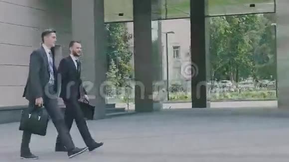 两个自信的年轻商人正在城市环境中步行到办公楼视频的预览图