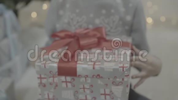 近景兴奋快乐男孩打开圣诞礼物盒惊讶地坐在新年树附近视频的预览图