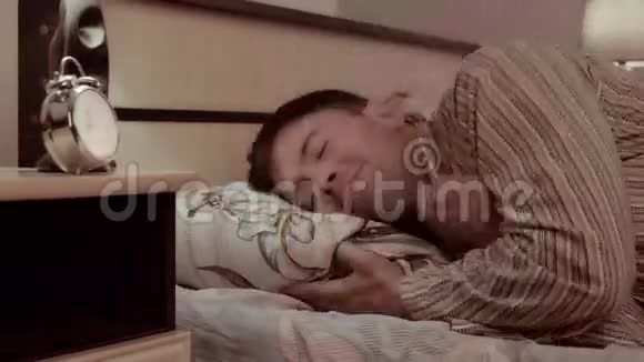 一个英俊的年轻人躺在床上微笑着睁大眼睛躲在毯子下面视频的预览图