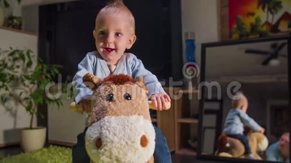 一个矮小的孩子在骑毛绒马时微笑着视频的预览图