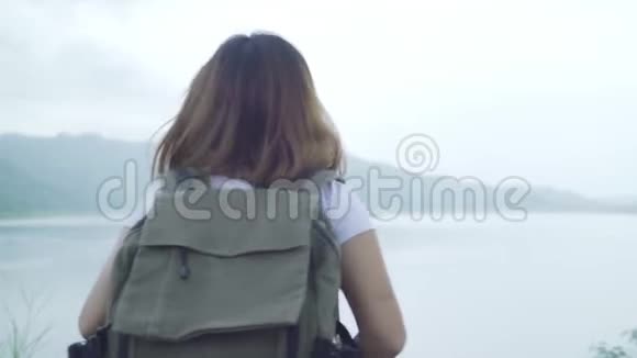 徒步旅行的徒步旅行女背包客在雨天在湖边的森林里自由行走视频的预览图