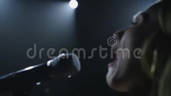 在黑色的烟雾背景上用麦克风特写歌手的脸歌手在舞台上唱一首歌视频的预览图