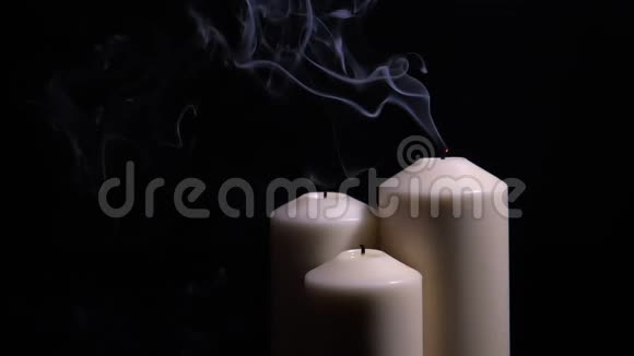 三支熄灭的蜡烛在黑色背景上冒烟视频的预览图