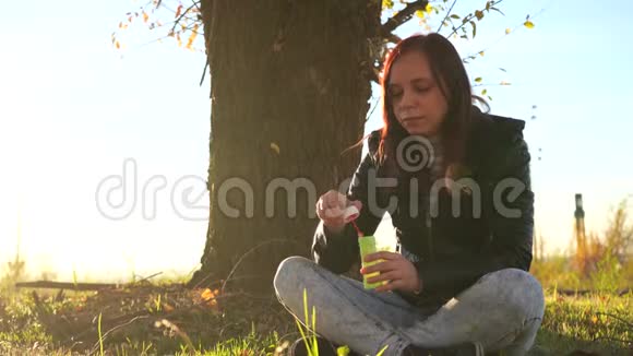 女人在户外吹肥皂泡在公园里玩得开心的少女吹肥皂泡视频的预览图